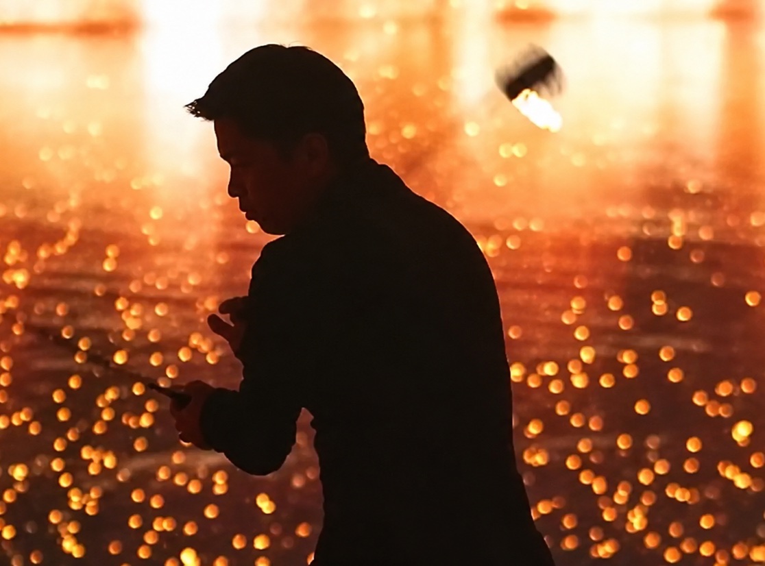 A performer silhouetted against a field of hundreds of small flames.