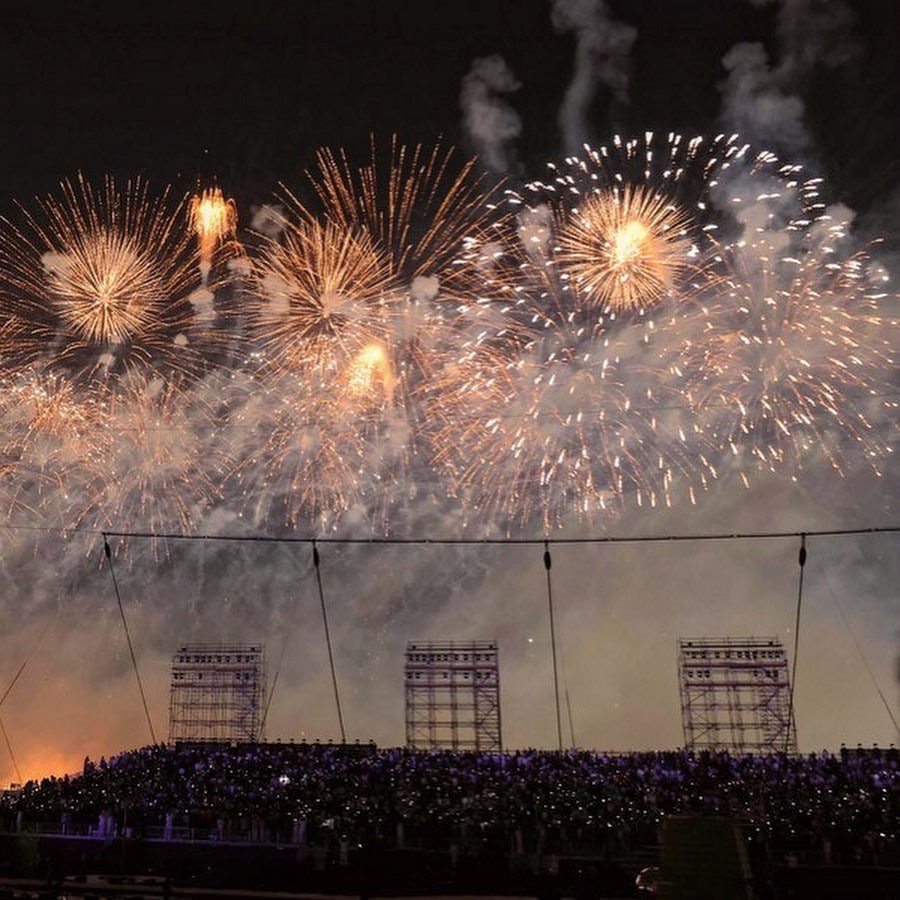Fireworks filling the sky above a packed stadium stand.